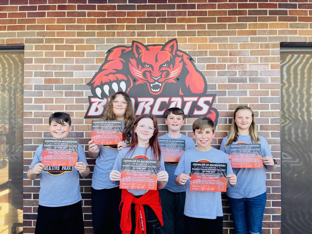 group of 4 children posing in front of bearcat sign