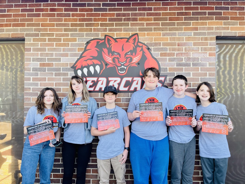 group of 6 children posing in front of bearcat sign