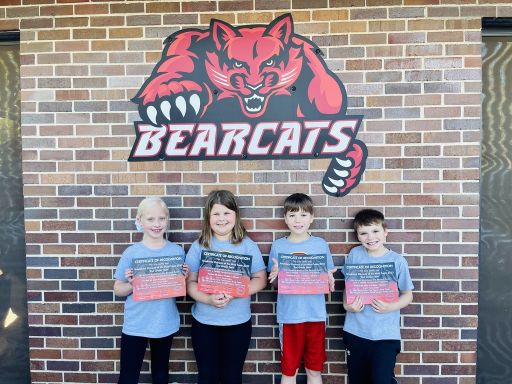 group of 4 children posing in front of bearcat sign